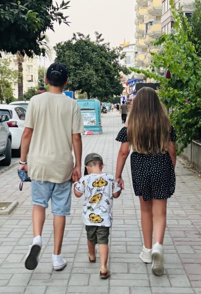 Three children walking along the street holding hands