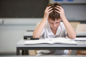 Boy at school desk with his head in his hands